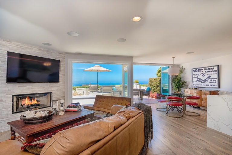Open concept living room with folding frameless glass doors overlooking the ocean.