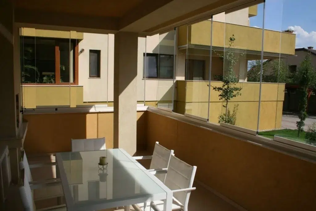 Apartment patio with staggered frameless sliding glass windows.