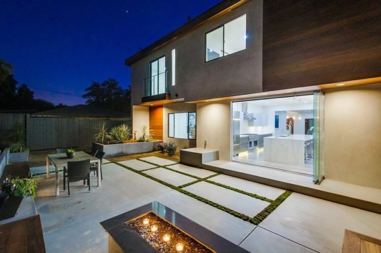 Patio with fireplace looking into kitchen with stacked frameless sliding glass doors.