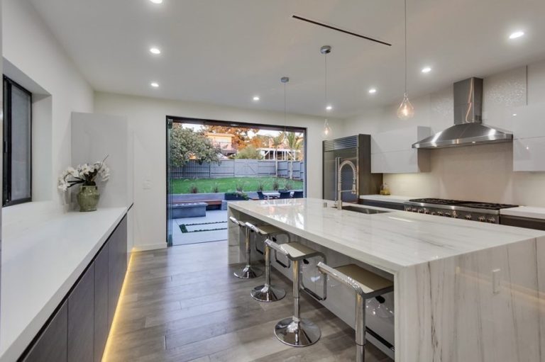 Kitchen with view of backyard with stacked frameless sliding glass doors.