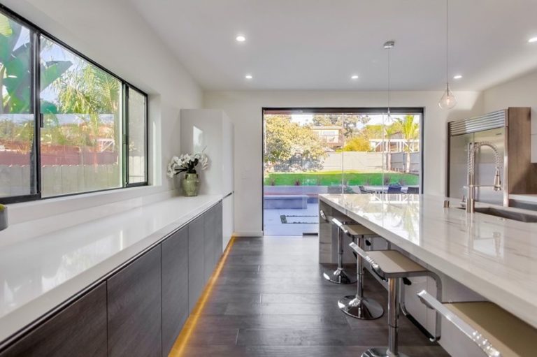 Kitchen with view of backyard with enclosed frameless sliding glass doors.