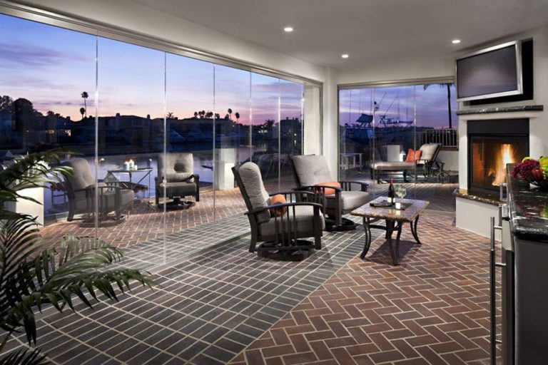 Looking at living room and patio with enclosed frameless sliding glass doors.