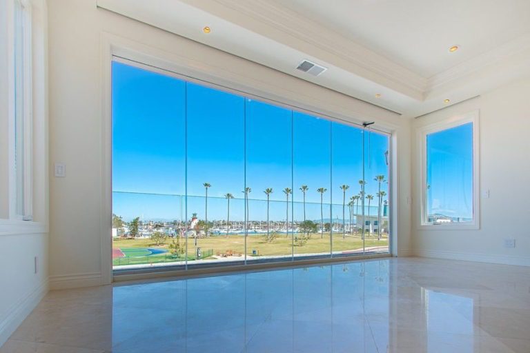 Looking from empty living room into bay with enclosed frameless sliding glass doors.