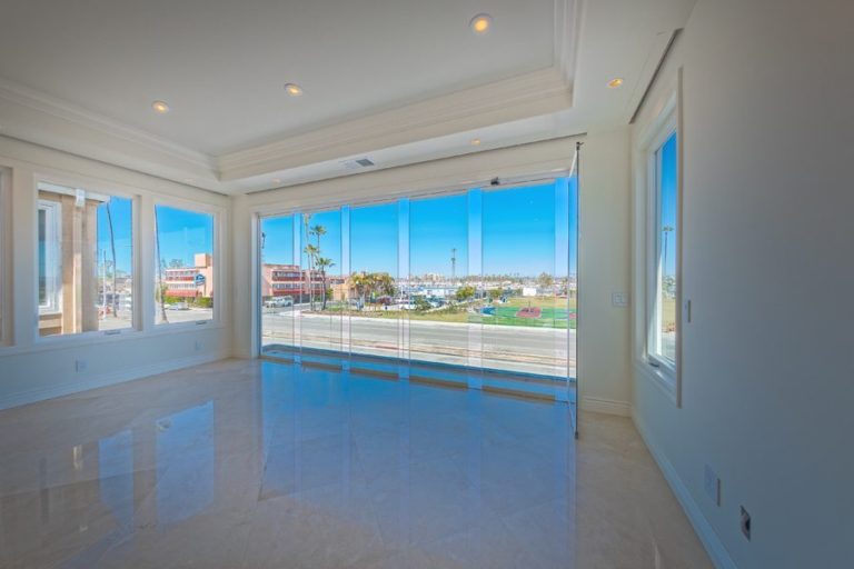 Looking from empty living room into bay with staggered frameless sliding glass doors.