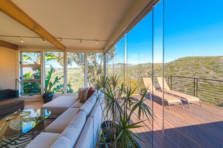 Living room and patio with staggered frameless sliding glass doors.