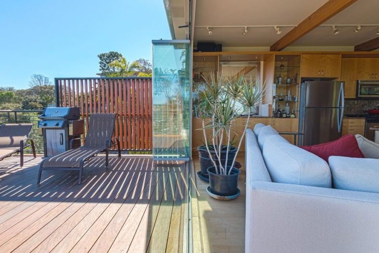 Patio and open concept living room with stacked frameless sliding glass doors.