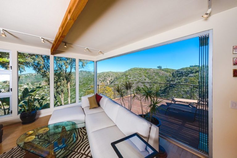 Living room with patio and stacked frameless sliding glass doors.