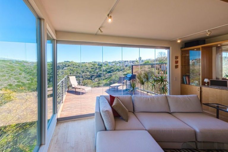 Living room and patio with enclosed frameless sliding glass doors.