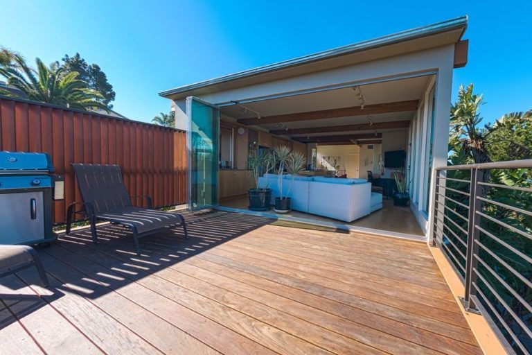 Patio looking into living room with stacked frameless sliding glass doors.