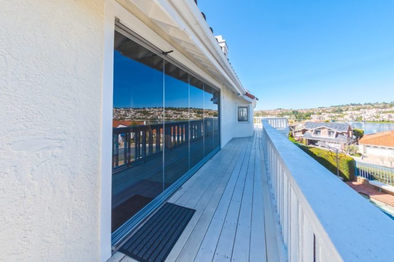 Outdoor deck with closed frameless sliding glass doors overlooking the outside.