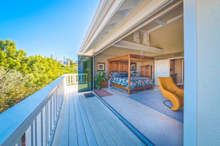 Outdoor deck with stacked frameless sliding glass doors creating an open space with the bedroom.