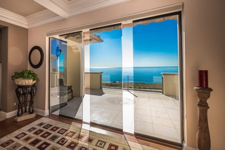 Living room with staggered frameless glass sliding glass doors and views of ocean.