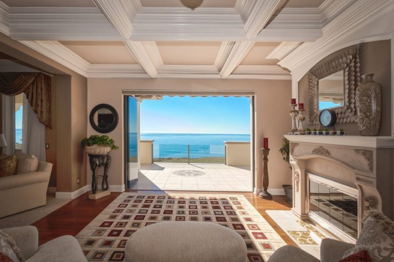 Living room with view of ocean and stacked frameless glass sliding doors.