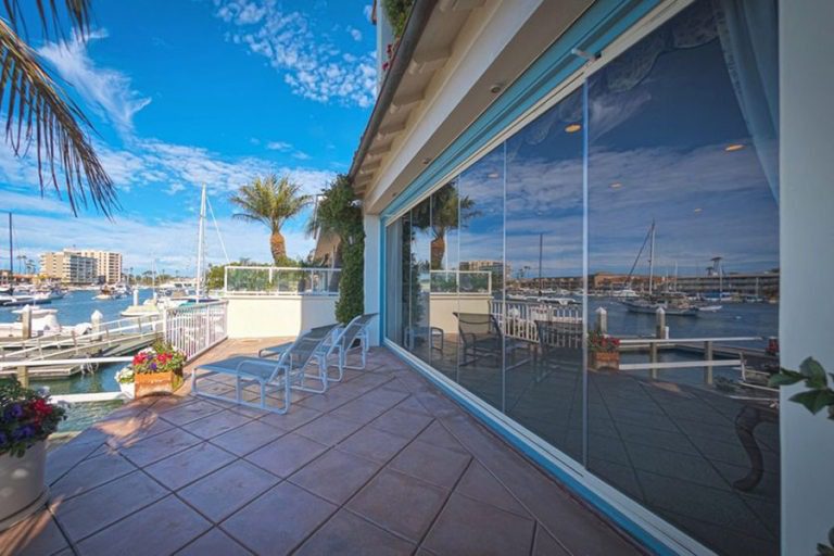 Outdoor patio with view of the bay and frameless sliding glass doors connecting to the living area.