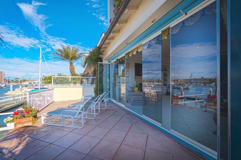 Outdoor patio with partially open frameless sliding glass doors.