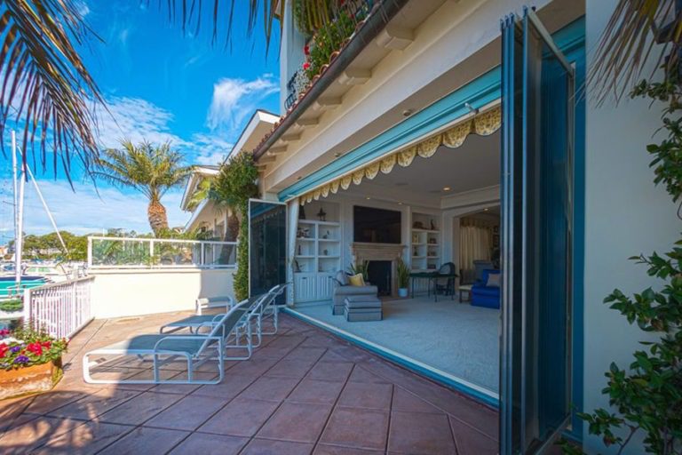 Outdoor patio with view of the bay and stacked frameless sliding glass doors connecting to the living area.