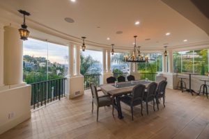 Enclosed frameless sliding glass door dining room patio with view of hill.