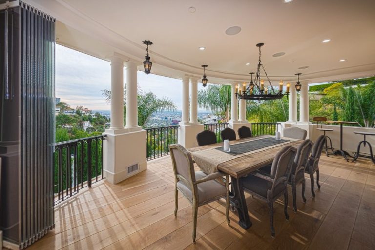 Stacked frameless sliding glass door dining room patio with view of hill.