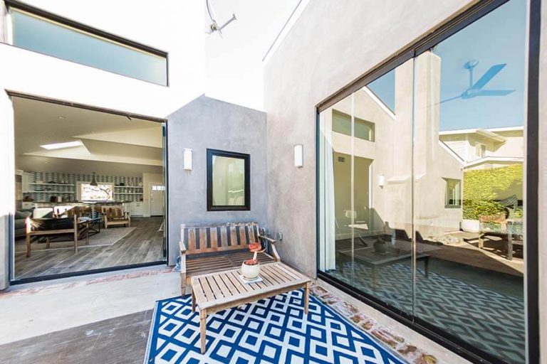 Outdoor patio featuring closed sliding glass doors on the right and stacked sliding glass doors on the left looking into the living area.