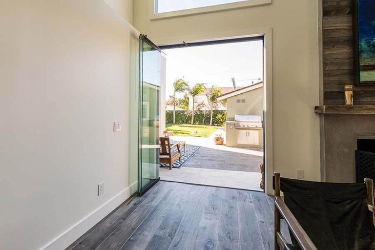 Stacked frameless sliding glass panels overlooking the back yard from living area.