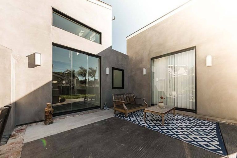 Outdoor patio in between two buildings featuring closed sliding glass doors.