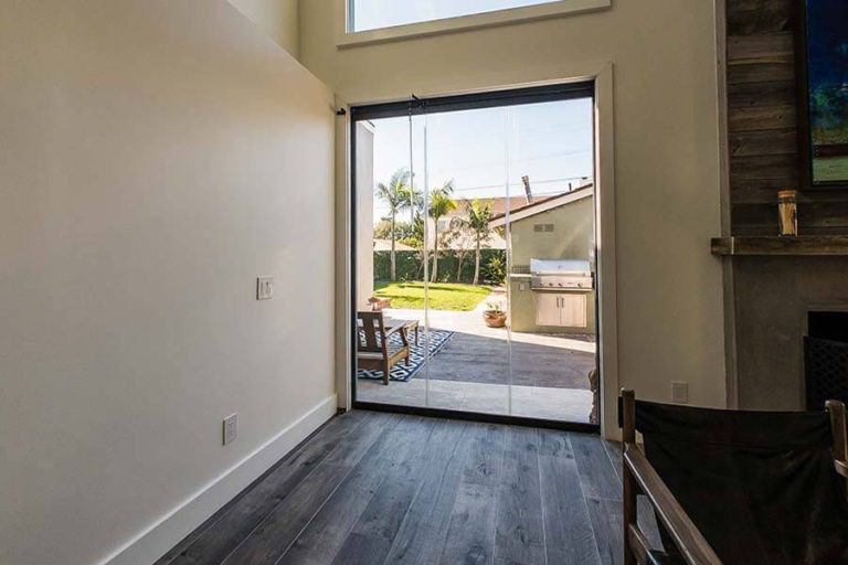 Closed frameless sliding glass panels overlooking the back yard from living area.