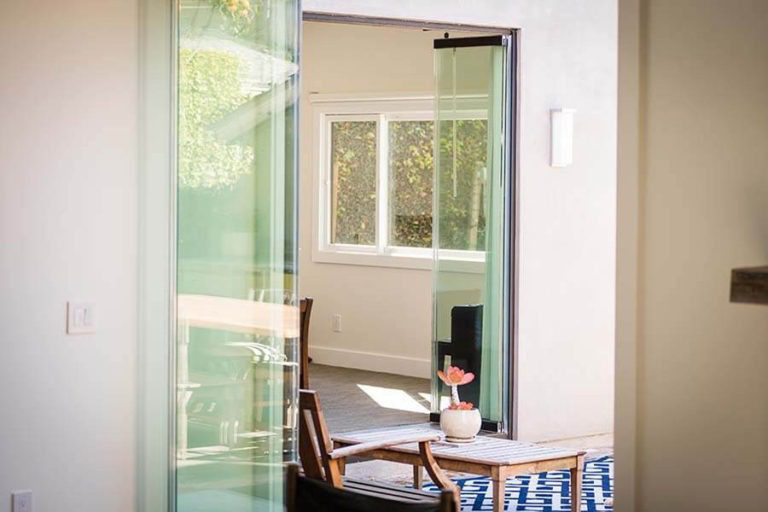 Stacked frameless glass doors looking into the adjacent room.