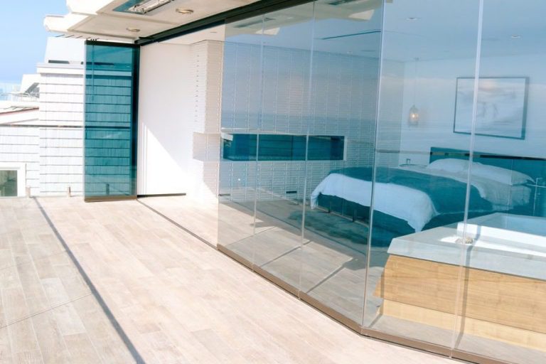 Looking from patio into bedroom with an opening in enclosed frameless sliding glass doors.