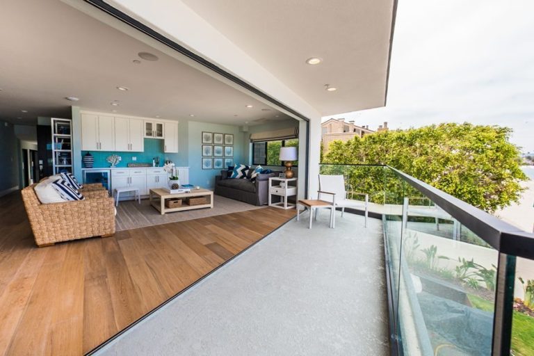 Looking from patio into living room with opened frameless sliding glass doors.