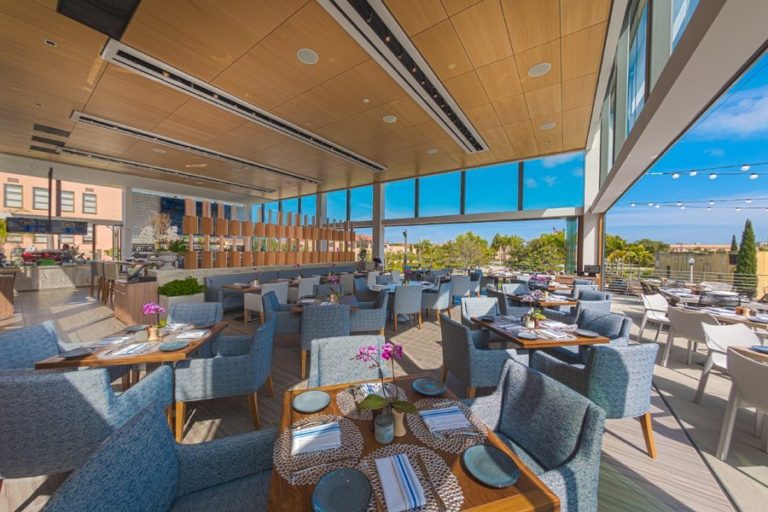 Restaurant dining area with stacked frameless sliding glass doors.