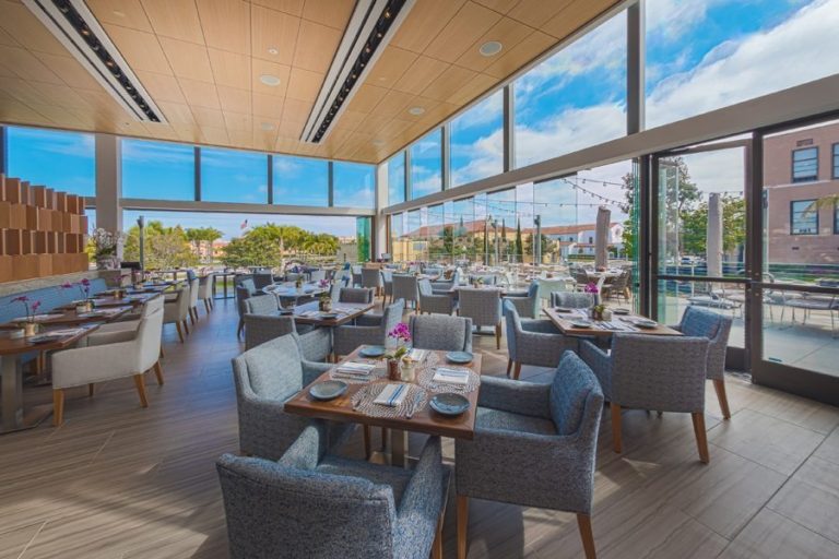 Restaurant dining area with staggered frameless sliding glass doors.