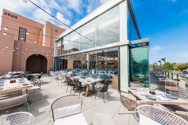 Restaurant patio dining area with enclosed frameless sliding glass doors.