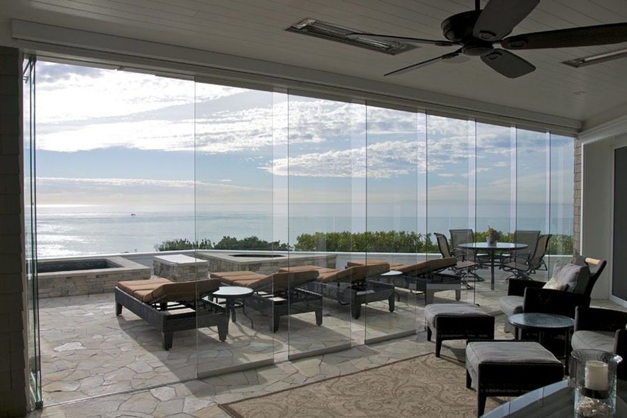 Staggered frameless sliding glass door with view of patio and ocean.