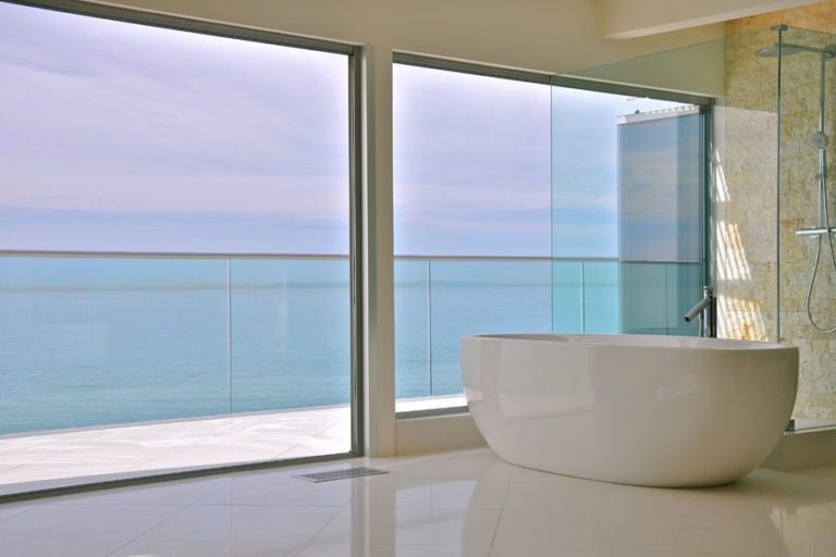 Intimate bath tub with stacked frameless sliding glass doors and windows.