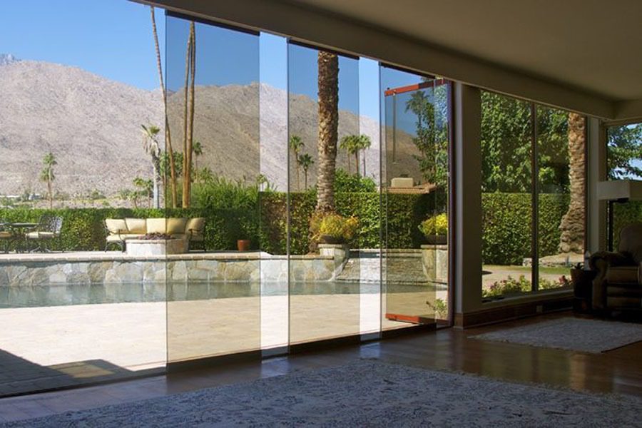 Living room with view of pool from staggered frameless sliding glass doors.