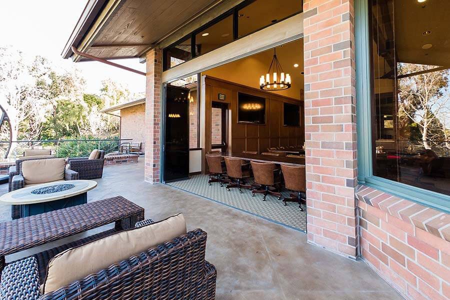 Outdoor patio looking into country club with stacked frameless sliding glass doors.
