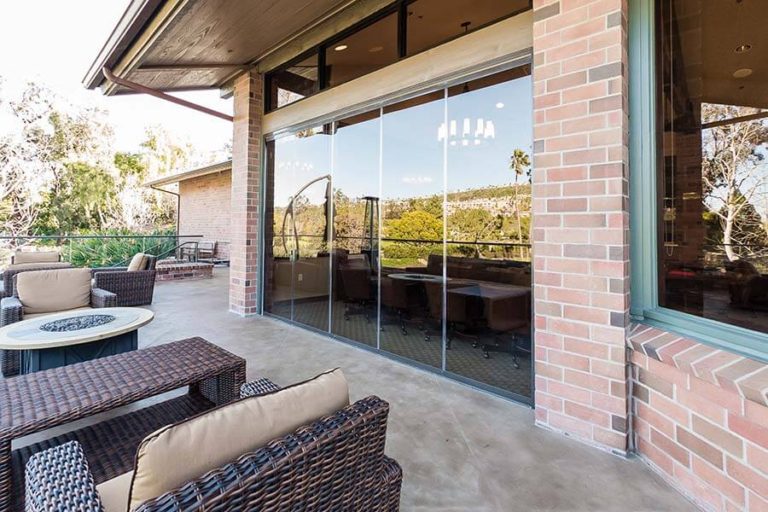 Outdoor patio looking into country club through frameless sliding glass doors.