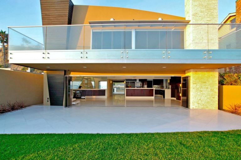 Looking into kitchen from backyard with stacked frameless glass doors.