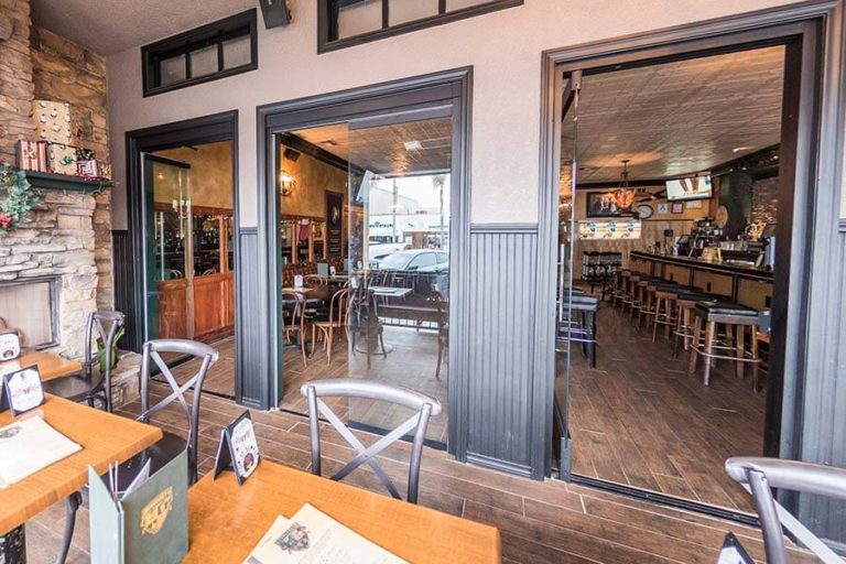 Restaurant tables with opened frameless sliding glass doors.