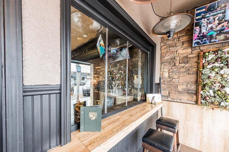 Frameless glass window separating bar counter from the outdoor dining area.