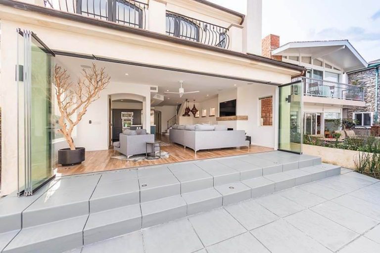 View of the living room from outdoor area through fully stacked sliding glass doors.