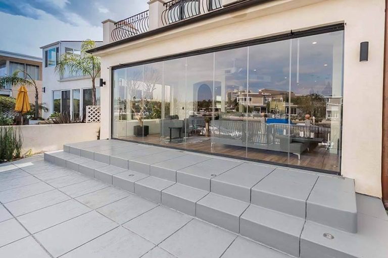 Frameless sliding glass doors connecting living room with patio.