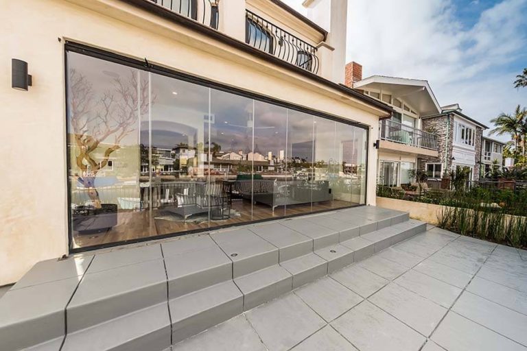 Closed frameless sliding glass doors connecting living room with patio.