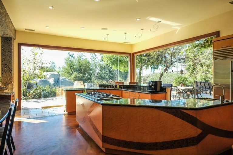 Open concept dining area and kitchen with closed frameless sliding glass doors showing the outdoors.