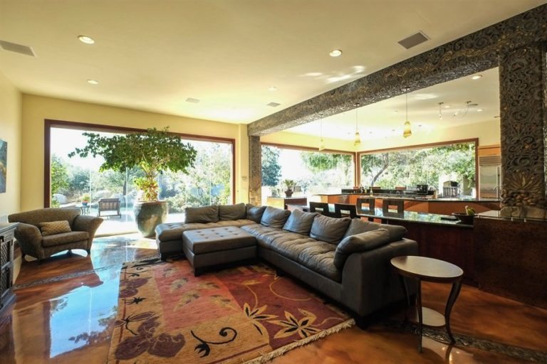 Open concept living room with dark brown sectional sofa and closed frameless sliding glass doors showing the outdoor patio.