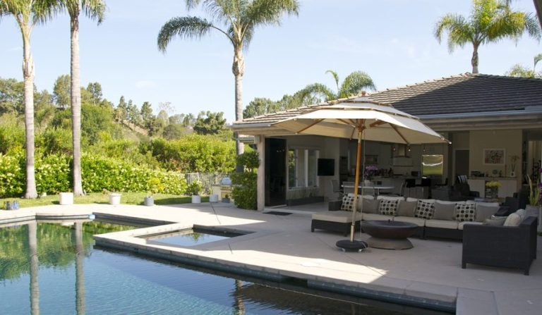 Backyard with pool looking into open concept kitchen and living room with stacked frameless glass sliding doors.