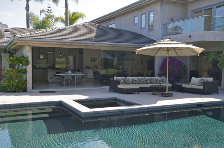 Pool with patio and half enclosed, half opened frameless sliding glass doors.