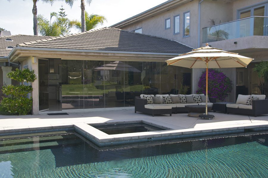 Pool and patio with enclosed frameless glass sliding doors and an open panel.