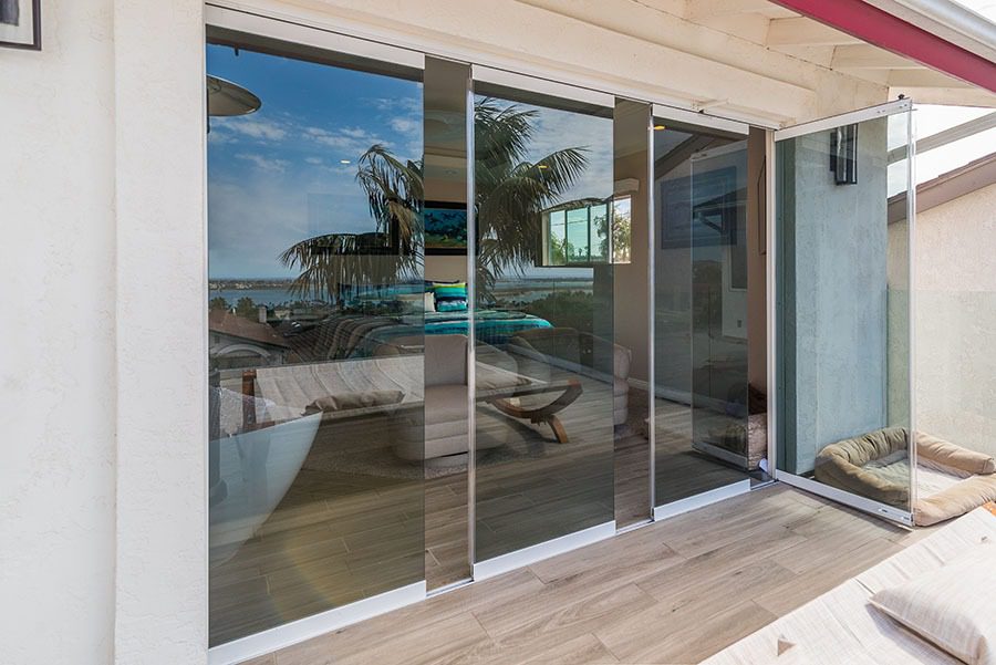 Patio and staggered frameless sliding glass door with one door frame swung open.