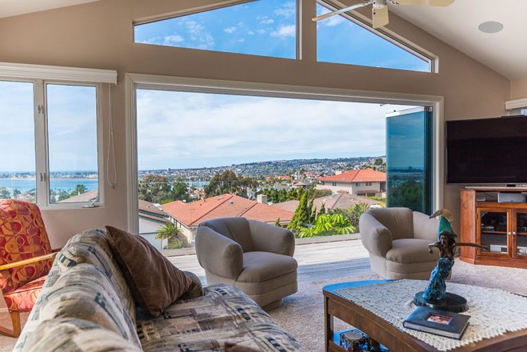 From living room looking out into bay with frameless sliding glass doors stack to one side.